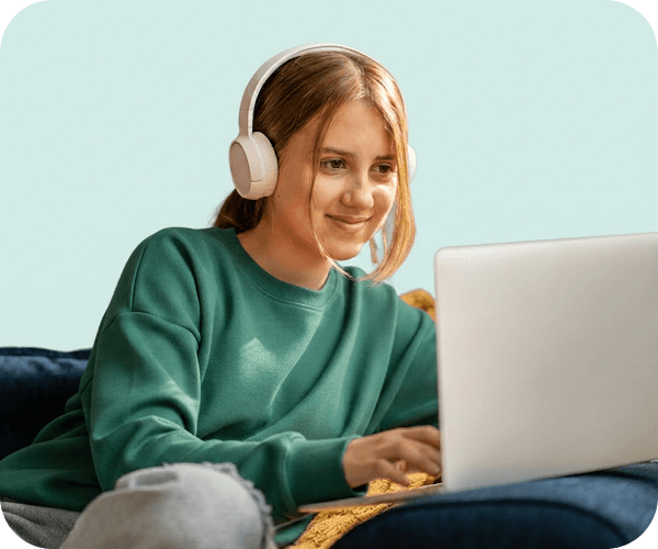 Student in headphones smiling while studying on a laptop